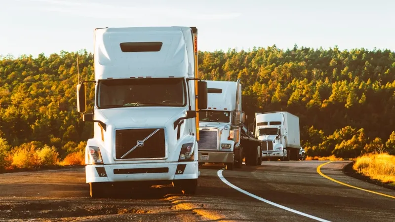 three white trucks on the road